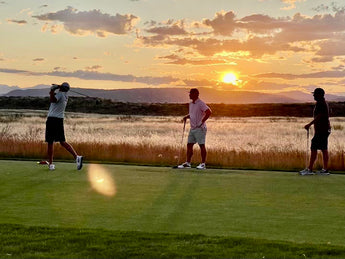 3 Men Playing Golf in front of a sunset